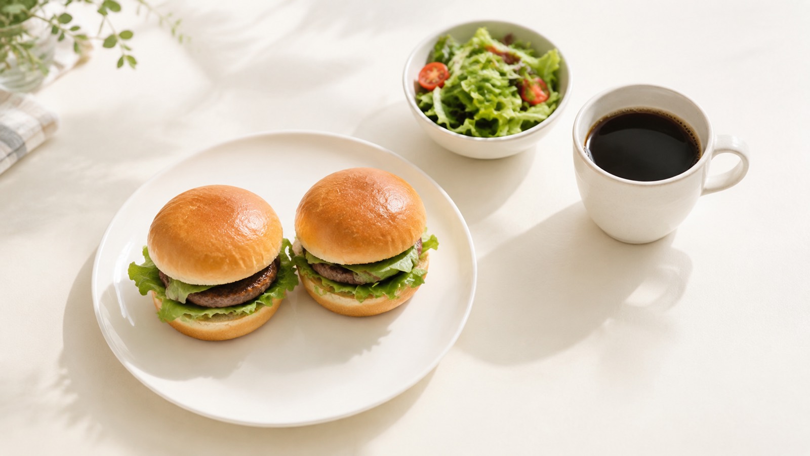 白い皿に並んだハンバーガー2個とサラダとブラックコーヒー